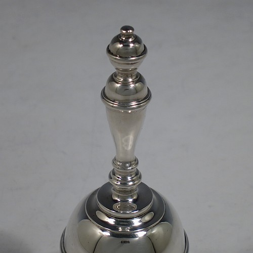 A Sterling Silver Georgian style table bell having a plain round body with applied reeded borders, a cast baluster handle, and an original silver clapper. Made by Carrington and Co., of London in 1929. The dimensions of this fine hand-made silver table bell are height 10.5 cms (4.25 inches), diameter at base 6 cms (2.3 inches), and it weighs approx. 165g (5.3 troy ounces).   