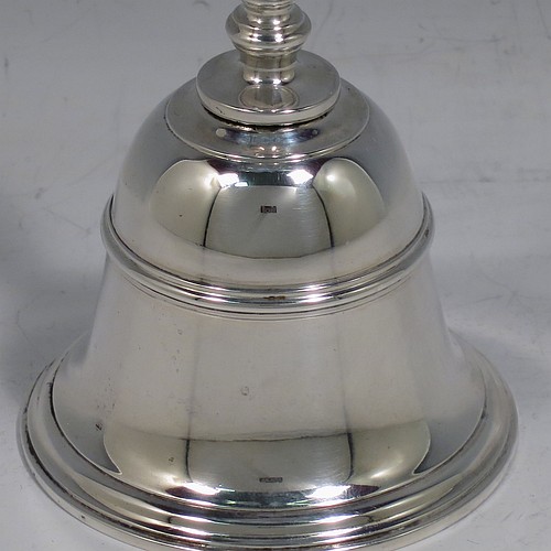 A Sterling Silver Georgian style table bell having a plain round body with applied reeded borders, a cast baluster handle, and an original silver clapper. Made by Carrington and Co., of London in 1929. The dimensions of this fine hand-made silver table bell are height 10.5 cms (4.25 inches), diameter at base 6 cms (2.3 inches), and it weighs approx. 165g (5.3 troy ounces).   