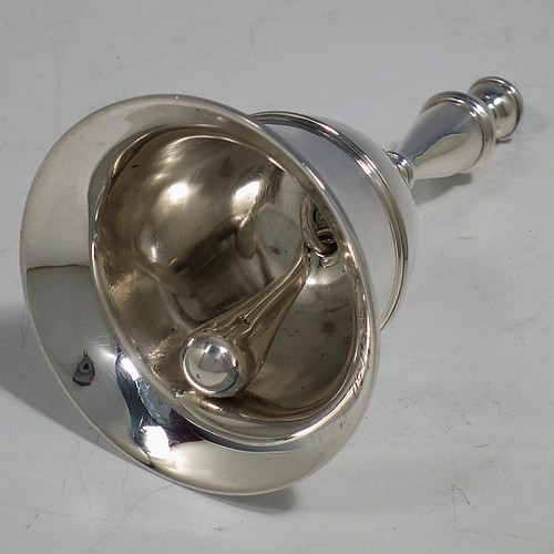 A Sterling Silver Georgian style table bell having a plain round body with applied reeded borders, a cast baluster handle, and an original silver clapper. Made by Carrington and Co., of London in 1929. The dimensions of this fine hand-made silver table bell are height 10.5 cms (4.25 inches), diameter at base 6 cms (2.3 inches), and it weighs approx. 165g (5.3 troy ounces).   