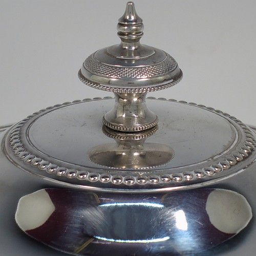 An Antique Victorian Silver Plated biscuit box, having a round body with applied bead-edged borders, straight sides and hand-chased swags of bead-work in a neoclassical style, a hinged domed lid with cast finial, and all sitting on an attached plate with three cast claw and ball feet. Made by James Thompson of Sheffield in ca. 1880. The dimensions of this fine hand-made antique silver-plated biscuit box are height 18 cms (7 inches), and diameter at base 18 cms (7 inches). Please note that this item is crested.