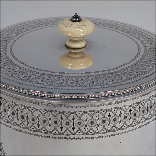 A very pretty Antique Victorian Silver Plated biscuit box, having a round body with straight sides and applied bead-edged borders, with very pretty hand-engraved bands of geometrical and floral work, a hinged flat lid with bone finial, and all sitting on an attached plate with four cast scroll and shell feet. Made by Elkington and Co., of Sheffield in ca. 1880. The dimensions of this fine hand-made antique silver-plated biscuit box are height 16 cms (6.3 inches), and diameter at base 18 cms (7 inches).    