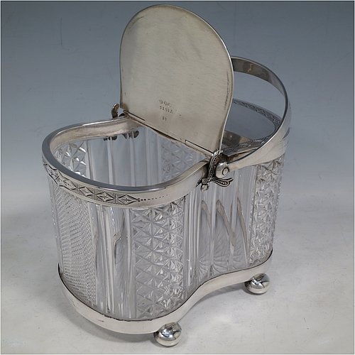 An Antique Victorian silver plated and cut crystal biscuit jar, having a hobnail and fluted cut  crystal body, a hand-engraved mechanically double-hinged lid with a swing handle, and all sitting on a base with four cushion feet. Made by Thomas Wilkinson & Sons of Sheffield in ca. 1890. The dimensions of this fine hand-made antique silver-plated and hand-cut crystal biscuit jar are height inc. handle 23 cms (9 inches), length of base 19 cms (7.5 inches), and width of base 14 cms (5.5 inches).   