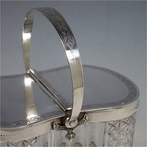 An Antique Victorian silver plated and cut crystal biscuit jar, having a hobnail and fluted cut  crystal body, a hand-engraved mechanically double-hinged lid with a swing handle, and all sitting on a base with four cushion feet. Made by Thomas Wilkinson & Sons of Sheffield in ca. 1890. The dimensions of this fine hand-made antique silver-plated and hand-cut crystal biscuit jar are height inc. handle 23 cms (9 inches), length of base 19 cms (7.5 inches), and width of base 14 cms (5.5 inches).   