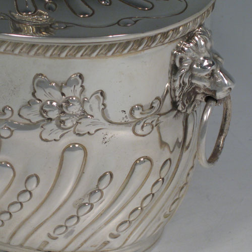    Antique Victorian sterling silver biscuit box, having an oval body with hand-chased fluting and floral decoration, hinged lid with finial, and two lion-mask ring handles. Height 18 cms (7 inches), length 18.5 cms (7.25 inches), width 13 cms (5 inches). Weight approx. 682g (22 troy ounces).