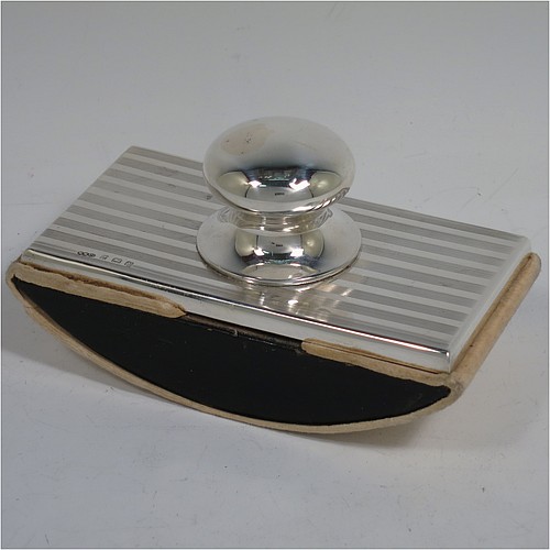 A Sterling Silver Rocker Blotter, having a rectangular body with engine-turned reeded decoration, a black stained wooden rocker base, and a plain round bellied handle that screws in to secure the rocker base and blotting paper to the upper body. Made by Wilmot Manufacturing Silversmiths of Birmingham in 1923. The dimensions of this fine hand-made silver rocker blotter are length 11.5 cms (4.5 inches), height 6.5 cms (2.5 inches), and width 6.5 cms (2.5 inches).