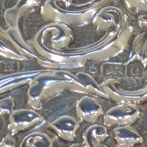 A very pretty Antique Edwardian Sterling Silver Rocker Blotter, having a rectangular body with rounded corners and hand-chased floral and scroll decoration, a leather covered rocker base, and a swirl fluted round handle that screws in to secure the rocker base and blotting paper to the upper body. Made by Henry Miller of Birmingham in 1902. The dimensions of this fine hand-made antique silver rocker blotter are length 11.5 cms (4.5 inches), height 6.5 cms (2.5 inches), and width 7 cms (2.75 inches).  