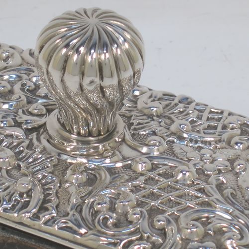 A very pretty Antique Edwardian Sterling Silver Rocker Blotter, having a rectangular body with rounded corners and hand-chased floral and scroll decoration, a leather covered rocker base, and a swirl fluted round handle that screws in to secure the rocker base and blotting paper to the upper body. Made by Henry Miller of Birmingham in 1902. The dimensions of this fine hand-made antique silver rocker blotter are length 11.5 cms (4.5 inches), height 6.5 cms (2.5 inches), and width 7 cms (2.75 inches).  