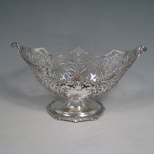    Antique Edwardian sterling silver bon-bon dish, having an oval hand-pierced body, applied shell and gadroon borders, cast shell and fluted handles, and sitting on a pedestal foot. Made by Jackson and Fullerton of London in 1904. Height 14 cms (5.5 inches), length 24 cms (9.5 inches), width 13 cms (5 inches). Weight approx. 383g (12.4 troy ounces).