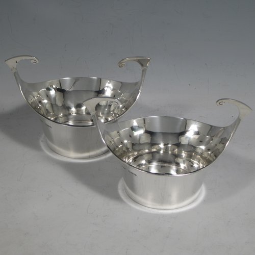 Antique Edwardian sterling silver pair of bon-bon dishes, having plain round bodies, with very unusual flying scroll handles, and each sitting on flat bases. Originally imported into, and hallmarked for, London in 1905. The dimensions of this fine pair of hand-made silver bon-bon dishes are width across handles 12 cms (4.75 inches), height 8 cms (3.25 inches), and they weigh a total of 180g (5.3 troy ounces).   