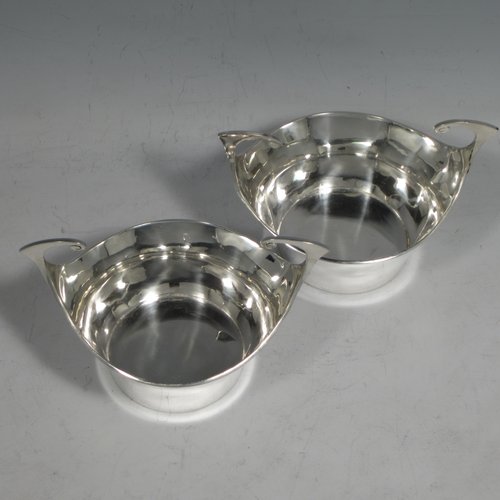 Antique Edwardian sterling silver pair of bon-bon dishes, having plain round bodies, with very unusual flying scroll handles, and each sitting on flat bases. Originally imported into, and hallmarked for, London in 1905. The dimensions of this fine pair of hand-made silver bon-bon dishes are width across handles 12 cms (4.75 inches), height 8 cms (3.25 inches), and they weigh a total of 180g (5.3 troy ounces).   