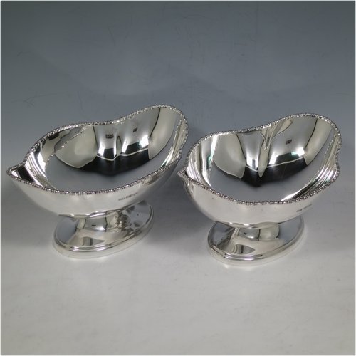 An Antique Sterling Silver pair of bon-bon dishes, having plain oval bodies, with applied and shaped egg & dart borders, and sitting on pedestal feet. Made by Henry Atkins of Sheffield in 1911. The dimensions of this fine pair of hand-made silver bon-bon dishes are length 16 cms (6.3 inches), width 11.5 cms (4.5 inches), height 8 cms (3 inches), and they weigh a total of approx. 413g (13.3 troy ounces).   