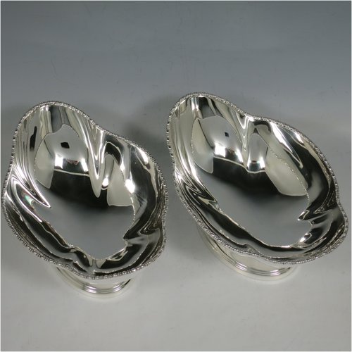 An Antique Sterling Silver pair of bon-bon dishes, having plain oval bodies, with applied and shaped egg & dart borders, and sitting on pedestal feet. Made by Henry Atkins of Sheffield in 1911. The dimensions of this fine pair of hand-made silver bon-bon dishes are length 16 cms (6.3 inches), width 11.5 cms (4.5 inches), height 8 cms (3 inches), and they weigh a total of approx. 413g (13.3 troy ounces).   