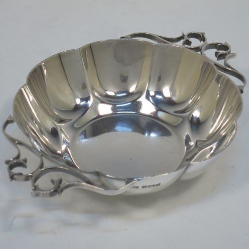 A very pretty Antique Edwardian Sterling Silver pair of bon-bon dishes, having rounded bodies with hand-chased lobed decoration, with beautiful scroll work side-handles, and all sitting on flat bases. Made by Roberts and Belk of Sheffield in 1908. The dimensions of this fine hand-made pair of antique silver bon-bon dishes  are length (inc. handles) 16 cms (6.25 inches), diameter 12 cms (4.75 inches), height 3.5 cms (1.3 inches), and they weigh a total of approx. 310g (10 troy ounces).   