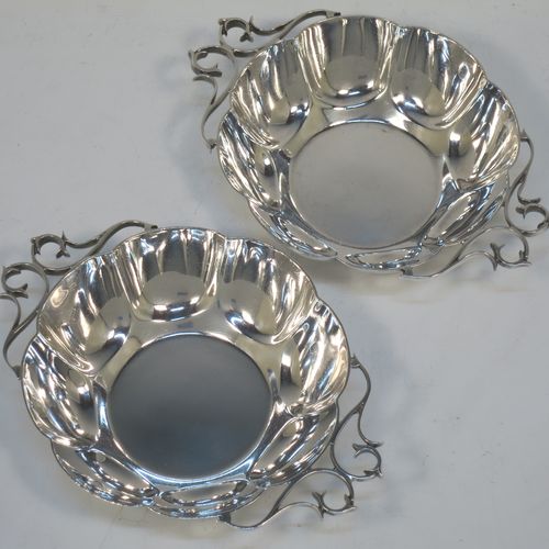 A very pretty Antique Edwardian Sterling Silver pair of bon-bon dishes, having rounded bodies with hand-chased lobed decoration, with beautiful scroll work side-handles, and all sitting on flat bases. Made by Roberts and Belk of Sheffield in 1908. The dimensions of this fine hand-made pair of antique silver bon-bon dishes  are length (inc. handles) 16 cms (6.25 inches), diameter 12 cms (4.75 inches), height 3.5 cms (1.3 inches), and they weigh a total of approx. 310g (10 troy ounces).   