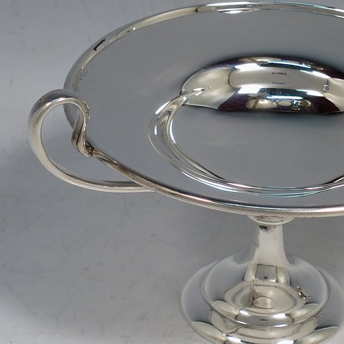 An Antique Edwardian Sterling Silver pair of bon-bon dishes, having plain round bodies, with applied reeded borders and two looped side handles, all raised above and sitting on plain round pedestal feet. Made by Holland, Aldwinkle & Slater  of London in 1907. The dimensions of these fine hand-made antique silver bon-bon dishes are height 9 cms (3.5 inches), diameter 11.5 cms (4.5 inches), and they weigh a total of approx. 241g (7.8 troy ounces).    