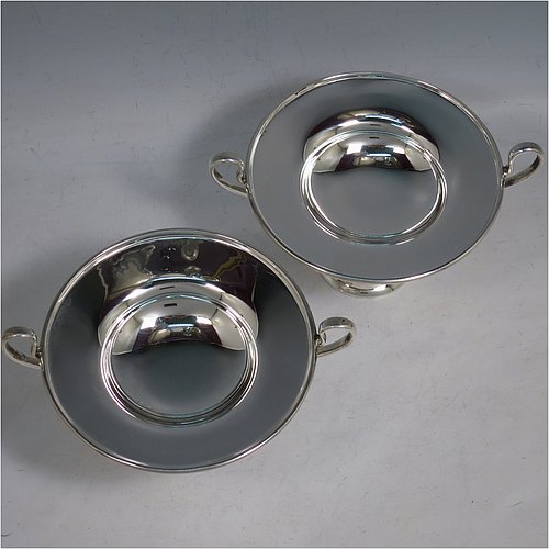 An Antique Edwardian Sterling Silver pair of bon-bon dishes, having plain round bodies, with applied reeded borders and two looped side handles, all raised above and sitting on plain round pedestal feet. Made by Holland, Aldwinkle & Slater  of London in 1907. The dimensions of these fine hand-made antique silver bon-bon dishes are height 9 cms (3.5 inches), diameter 11.5 cms (4.5 inches), and they weigh a total of approx. 241g (7.8 troy ounces).    