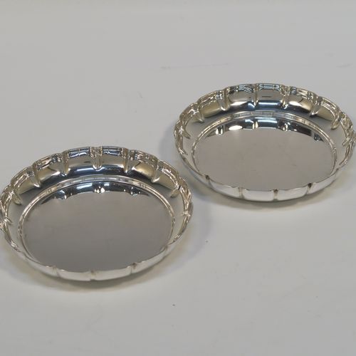 An elegant Sterling Silver pair of bon-bon dishes, having plain round bodies, with hand-chased scalloped raised borders, and sitting on flat bases. This handsome pair of silver bon-bon dishes were made by Bryan Savage of London in 1973. The dimensions of these fine hand-made silver bon-bon dishes are height 1.5 cms (0.5 inches), diameter 9 cms (3.5 inches), and they weigh a total of approx. 112g (3.6 troy ounces).   