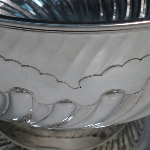 An Antique Victorian Sterling Silver large table bowl, having a round body with an applied reeded border and hand-chased half swirl-fluted decoration, all sitting on a pedestal foot which is also fluted. Made by Sibray, Hall & Co., of London in 1897. The dimensions of this fine hand-made antique silver bowl are diameter 25.5 cms (10 inches), height 19 cms (7.5 inches), and it weighs approx. 1,041g (33.6 troy ounces).   