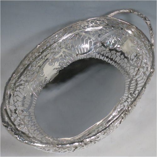 A Sterling Silver large table bowl, having an oval body with hand-pierced floral decoration, an applied cast border with oak-leaf mounts, with two cast loop handles, and all sitting on four cast foliate feet with matching decoration. Made by Robert Pringle of Sheffield in 1951. The dimensions of this fine hand-made silver bowl are length 32 cms (12.5 inches), width 20 cms (8 inches), height 14 cms (5.5 inches), and it weighs approx. 898g (29 troy ounces).   