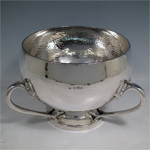 An Antique Edwardian heavy Sterling Silver Art Nouveau style table bowl, having a round hand-hammered and bellied body, with three cast scroll and tendril handles attached to a pedestal foot. Made by the Barker Brothers of Chester in 1909. The dimensions of this fine hand-made antique silver bowl are height 15 cms (6 inches), diameter at top of bowl 20 cms (8 inches), and it weighs approx. 44 troy ounces (1,370g).   