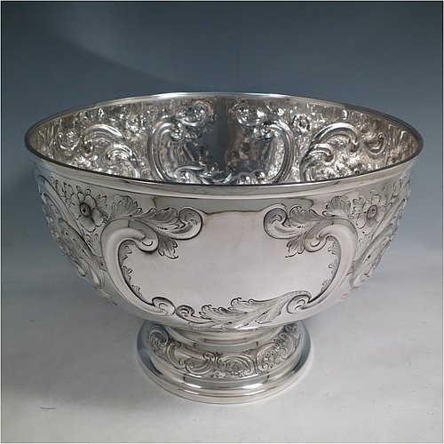 An Antique Victorian Silver Plated large table bowl, having a round hand-chased body with floral and scroll-work decoration, an applied plain border, with two vacant cartouches either side of the body, and sitting on a pedestal foot. Made in ca. 1880. The dimensions of this fine hand-made antique silver-plated table bowl are diameter 30.5 cms (15 inches), and height 21.5 cms (8.5 inches).   