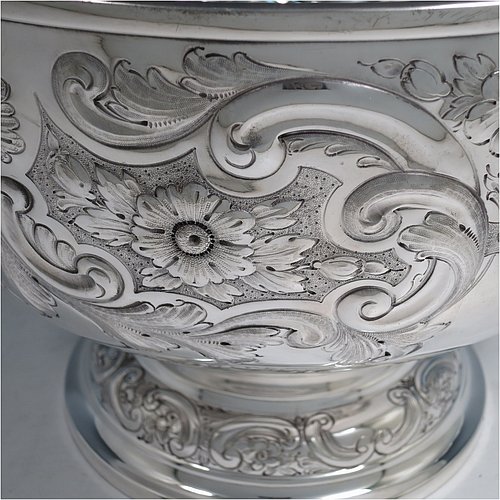 An Antique Victorian Silver Plated large table bowl, having a round hand-chased body with floral and scroll-work decoration, an applied plain border, with two vacant cartouches either side of the body, and sitting on a pedestal foot. Made in ca. 1880. The dimensions of this fine hand-made antique silver-plated table bowl are diameter 30.5 cms (15 inches), and height 21.5 cms (8.5 inches).   