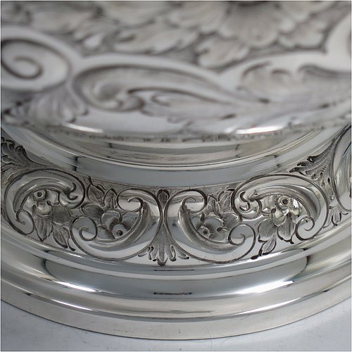 An Antique Victorian Silver Plated large table bowl, having a round hand-chased body with floral and scroll-work decoration, an applied plain border, with two vacant cartouches either side of the body, and sitting on a pedestal foot. Made in ca. 1880. The dimensions of this fine hand-made antique silver-plated table bowl are diameter 30.5 cms (15 inches), and height 21.5 cms (8.5 inches).   