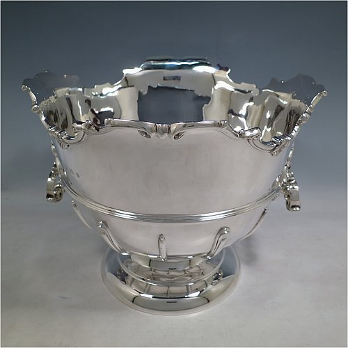 An Antique Edwardian Sterling Silver large table bowl, having a round body with an applied shell and scroll border, an applied reeded central band, together with cast hinged side-handles, and with applied strap-work on the lower body, and all sitting on a pedestal foot. Made by Williams of Birmingham in 1909. The dimensions of this fine hand-made large silver table bowl are diameter 29 cms (11.5 inches), height 23.5 cms (9.25 inches), and it weighs approx. 2,123g (68.5 troy ounces).    