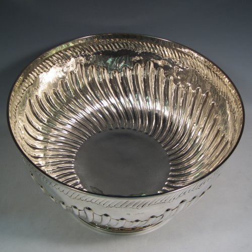 Antique Victorian sterling silver large Rose bowl, having a round body with hand-chased half swirl-fluted decoration, an applied reeded rim above another band of hand-chased fluting, and sitting on a pedestal foot with matching fluting. Made by Lamberts of London in 1893. The dimensions of this fine hand-made silver large table bowl are diameter 35 cms (13.75 inches), height 21 cms (8.25 inches), and it weighs approx. 1,767g (57 troy ounces).   