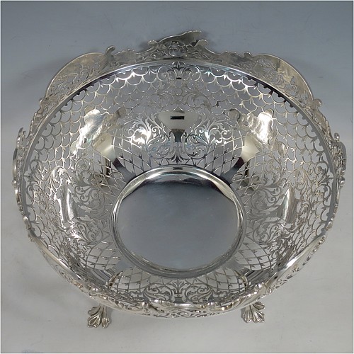 An Antique Edwardian Sterling Silver table bowl, having a round body with hand-pierced floral decoration, an applied floral & scroll border, and all sitting on four cast foliate feet. Made by Mappin & Webb of Sheffield in 1906. The dimensions of this fine hand-made antique silver bowl are diameter 24.5 cms (9.75 inches), height 14 cms (5.5 inches), and it weighs approx. 712g (23 troy ounces).