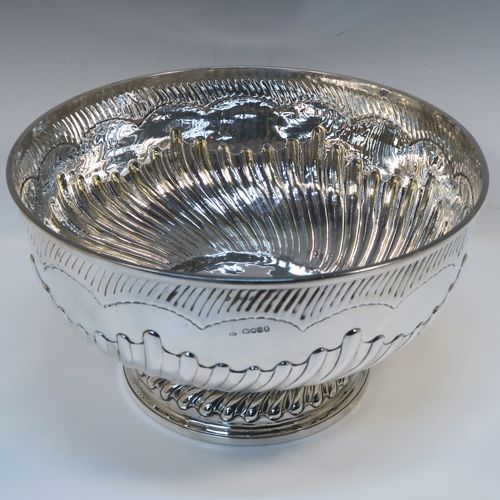 A rare and very large Antique late Georgian Sterling Silver table bowl, having a round body with an applied reeded top border and hand-chased half swirl-fluted decoration, all sitting on a pedestal foot which is also fluted. This large and handsome antique silver bowl was made by Thomas Barker of London in 1822. The dimensions of this fine hand-made antique silver bowl are diameter 35 cms (13.75 inches), height 19.5 cms (7.75 inches), and it weighs approx. 1,980g (63.9 troy ounces). Please note that this item has a full armorial crest on both sides.  