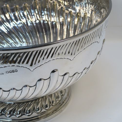 A rare and very large Antique late Georgian Sterling Silver table bowl, having a round body with an applied reeded top border and hand-chased half swirl-fluted decoration, all sitting on a pedestal foot which is also fluted. This large and handsome antique silver bowl was made by Thomas Barker of London in 1822. The dimensions of this fine hand-made antique silver bowl are diameter 35 cms (13.75 inches), height 19.5 cms (7.75 inches), and it weighs approx. 1,980g (63.9 troy ounces). Please note that this item has a full armorial crest on both sides.  