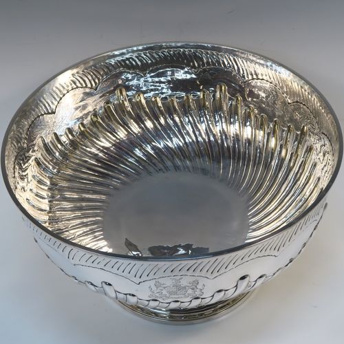 A rare and very large Antique late Georgian Sterling Silver table bowl, having a round body with an applied reeded top border and hand-chased half swirl-fluted decoration, all sitting on a pedestal foot which is also fluted. This large and handsome antique silver bowl was made by Thomas Barker of London in 1822. The dimensions of this fine hand-made antique silver bowl are diameter 35 cms (13.75 inches), height 19.5 cms (7.75 inches), and it weighs approx. 1,980g (63.9 troy ounces). Please note that this item has a full armorial crest on both sides.  