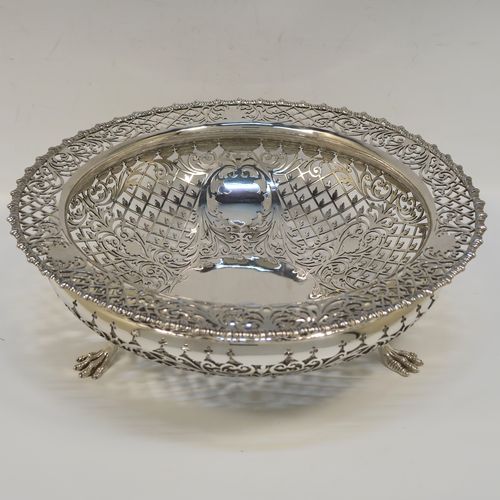 A very pretty Antique Sterling Silver fruit bowl, having a round body with hand-pierced floral and scroll decoration, an applied gadroon top border, and all sitting on three cast lions-paw feet. This beautiful silver fruit bowl was made by James Dixon and Sons of Sheffield in 1912. The dimensions of this fine hand-made antique silver fruit bowl are diameter 25.5 cms (10 inches), height 8 cms (3.25 inches), and it weighs approx. 772g (25 troy ounces).   