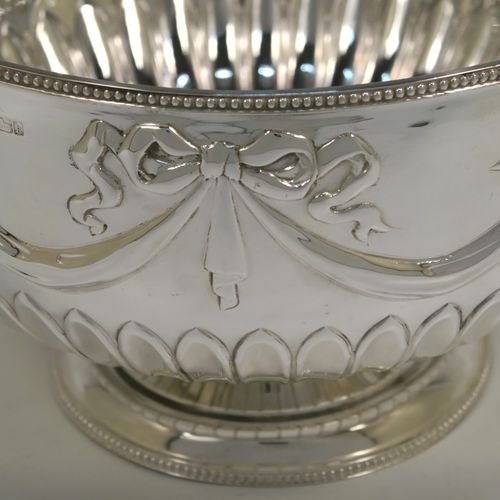 A very pretty Antique Edwardian Sterling Silver large Rose bowl, having a round body with hand-chased half fluted decoration, an applied bead-edged top border above another band of hand-chased swags and bows, and sitting on a pedestal foot with matching border. This beautiful antique silver bowl was made by William Hutton of Sheffield in 1902. The dimensions of this fine hand-made antique silver large table bowl are diameter 23 cms (9 inches), height 14.5 cms (5.75 inches), and it weighs approx. 620g (20 troy ounces).   