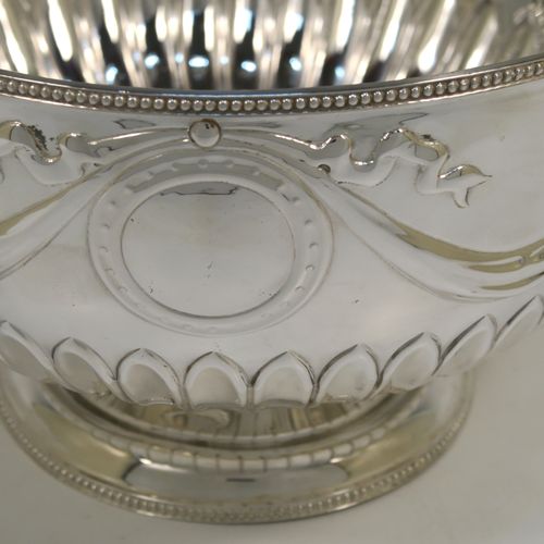 A very pretty Antique Edwardian Sterling Silver large Rose bowl, having a round body with hand-chased half fluted decoration, an applied bead-edged top border above another band of hand-chased swags and bows, and sitting on a pedestal foot with matching border. This beautiful antique silver bowl was made by William Hutton of Sheffield in 1902. The dimensions of this fine hand-made antique silver large table bowl are diameter 23 cms (9 inches), height 14.5 cms (5.75 inches), and it weighs approx. 620g (20 troy ounces).   