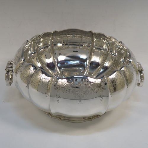 A very pretty and unusual Sterling Silver table bowl, having a round bellied body with a hand-engraved upper border showing scroll and floral decoration over hand-chased melon fluting, with two cast and hinged side handles, and all sitting on a pedestal foot. This beautiful silver bowl was made by Mappin and Webb of Sheffield in 1934. The dimensions of this fine hand-made silver bowl are diameter 25.5 cms (10 inches), height 12.5 cms (5 inches), and it weighs approx. 1,304g (42 troy ounces).  