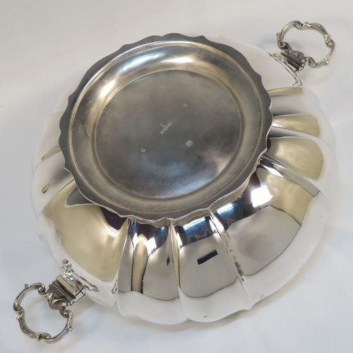 A very pretty and unusual Sterling Silver table bowl, having a round bellied body with a hand-engraved upper border showing scroll and floral decoration over hand-chased melon fluting, with two cast and hinged side handles, and all sitting on a pedestal foot. This beautiful silver bowl was made by Mappin and Webb of Sheffield in 1934. The dimensions of this fine hand-made silver bowl are diameter 25.5 cms (10 inches), height 12.5 cms (5 inches), and it weighs approx. 1,304g (42 troy ounces).  