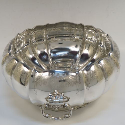 A very pretty and unusual Sterling Silver table bowl, having a round bellied body with a hand-engraved upper border showing scroll and floral decoration over hand-chased melon fluting, with two cast and hinged side handles, and all sitting on a pedestal foot. This beautiful silver bowl was made by Mappin and Webb of Sheffield in 1934. The dimensions of this fine hand-made silver bowl are diameter 25.5 cms (10 inches), height 12.5 cms (5 inches), and it weighs approx. 1,304g (42 troy ounces).  