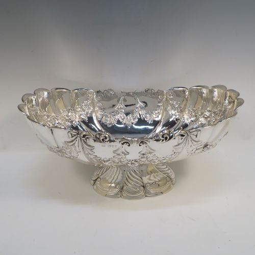 A very pretty and rare Antique Victorian Sterling Silver large oval Rose bowl, having an oval body with hand-chased fluting and garlands of floral decoration, an applied cast scroll top border, and sitting on a pedestal foot with matching decoration. This beautiful antique silver bowl was made by John Newton Mappin of London in 1894. The dimensions of this fine hand-made antique silver large table bowl are length 38 cms (15 inches), width 24 cms (9.5 inches), height 18.5 cms (7.25 inches), and it weighs approx. 1,203g (39 troy ounces).   