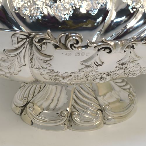 A very pretty and rare Antique Victorian Sterling Silver large oval Rose bowl, having an oval body with hand-chased fluting and garlands of floral decoration, an applied cast scroll top border, and sitting on a pedestal foot with matching decoration. This beautiful antique silver bowl was made by John Newton Mappin of London in 1894. The dimensions of this fine hand-made antique silver large table bowl are length 38 cms (15 inches), width 24 cms (9.5 inches), height 18.5 cms (7.25 inches), and it weighs approx. 1,203g (39 troy ounces).   