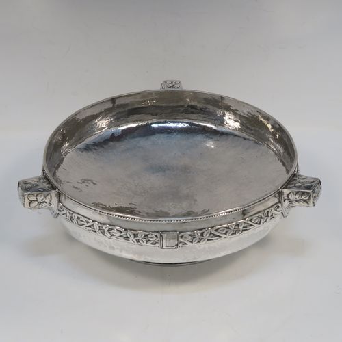 A very unusual and beautiful Antique Sterling Silver Art and Crafts style table bowl, having a round bellied body with hand-hammered decoration, an applied rope-twist top border, together with an applied central band of leaf design work, with three matching side-handles, and all sitting on a pedestal foot. This superb Arts and Crafts style  silver table bowl was made by John Sydney Reeve of  Birmingham in 1912. The dimensions of this fine hand-made antique silver bowl are height 8.5 cms (3.3 inches), diameter at top of bowl 24 cms (9.5 inches), and it weighs approx. 799g (25.8 troy ounces).   