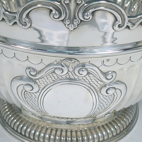 An Antique Edwardian Sterling Silver Montieth style bowl, having a round body with an applied scroll border, with hand-chased half-fluted decoration, together with two cast lion-mask side-handles, and sitting on a pedestal foot. Made by Elkington & Co.,of London in 1910. The dimensions of this fine hand-made antique silver table bowl are diameter 22 cms (8.75 inches), height 16.5 cms (6.5 inches), and it weighs approx. 930g (30 troy ounces).    