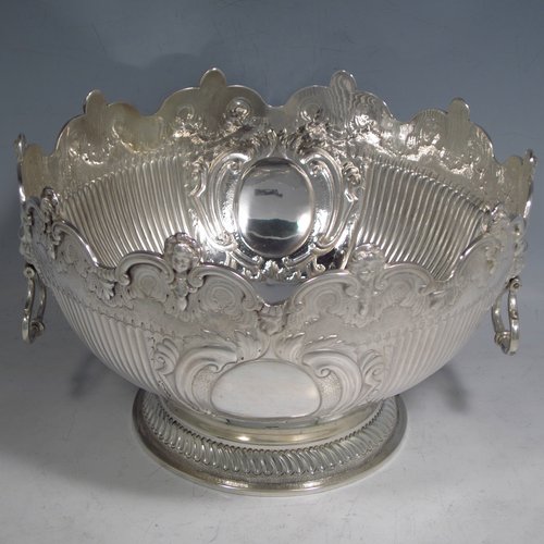 An Antique Victorian sterling silver Montieth style bowl, having a round body with an applied scroll and cast cherub-head border, with hand-chased floral and half-fluted decoration, together with two cast lion-mask and hinged side-handles, and sitting on a pedestal foot. Made by the Barnard Brothers of London in 1894. The dimensions of this fine hand-made silver table bowl are diameter 20 cms (8 inches), height 13 cms (5.25 inches), and it weighs approx. 653g (21 troy ounces).   