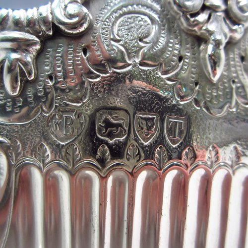 An Antique Victorian sterling silver Montieth style bowl, having a round body with an applied scroll and cast cherub-head border, with hand-chased floral and half-fluted decoration, together with two cast lion-mask and hinged side-handles, and sitting on a pedestal foot. Made by the Barnard Brothers of London in 1894. The dimensions of this fine hand-made silver table bowl are diameter 20 cms (8 inches), height 13 cms (5.25 inches), and it weighs approx. 653g (21 troy ounces).   