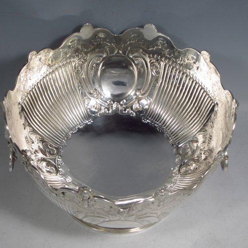 An Antique Victorian sterling silver Montieth style bowl, having a round body with an applied scroll and cast cherub-head border, with hand-chased floral and half-fluted decoration, together with two cast lion-mask and hinged side-handles, and sitting on a pedestal foot. Made by the Barnard Brothers of London in 1894. The dimensions of this fine hand-made silver table bowl are diameter 20 cms (8 inches), height 13 cms (5.25 inches), and it weighs approx. 653g (21 troy ounces).   