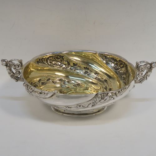 A very pretty Antique Victorian Sterling Silver bowl, having an oval body with hand-chased swirl fluting and floral decoration, with two cast figural side-handles, a gold-gilt interior, and sitting on an oval pedestal foot. This beautiful antique silver oval bowl was made by Charles Stuart Harris of London in 1891. The dimensions of this fine hand-made antique silver bowl are height 9 cms (3.5 inches), length 25 cms (9.75 inches), width 15 cms (6 inches), and it weighs approx. 316g (10.2 troy ounces).   