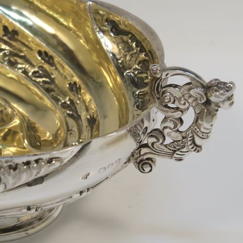 A very pretty Antique Victorian Sterling Silver bowl, having an oval body with hand-chased swirl fluting and floral decoration, with two cast figural side-handles, a gold-gilt interior, and sitting on an oval pedestal foot. This beautiful antique silver oval bowl was made by Charles Stuart Harris of London in 1891. The dimensions of this fine hand-made antique silver bowl are height 9 cms (3.5 inches), length 25 cms (9.75 inches), width 15 cms (6 inches), and it weighs approx. 316g (10.2 troy ounces).   