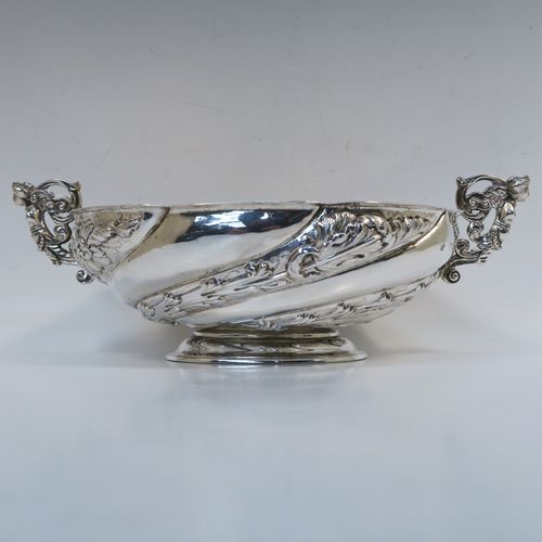 A very pretty Antique Victorian Sterling Silver bowl, having an oval body with hand-chased swirl fluting and floral decoration, with two cast figural side-handles, a gold-gilt interior, and sitting on an oval pedestal foot. This beautiful antique silver oval bowl was made by Charles Stuart Harris of London in 1891. The dimensions of this fine hand-made antique silver bowl are height 9 cms (3.5 inches), length 25 cms (9.75 inches), width 15 cms (6 inches), and it weighs approx. 316g (10.2 troy ounces).   