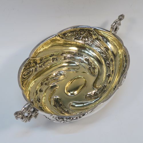 A very pretty Antique Victorian Sterling Silver bowl, having an oval body with hand-chased swirl fluting and floral decoration, with two cast figural side-handles, a gold-gilt interior, and sitting on an oval pedestal foot. This beautiful antique silver oval bowl was made by Charles Stuart Harris of London in 1891. The dimensions of this fine hand-made antique silver bowl are height 9 cms (3.5 inches), length 25 cms (9.75 inches), width 15 cms (6 inches), and it weighs approx. 316g (10.2 troy ounces).   